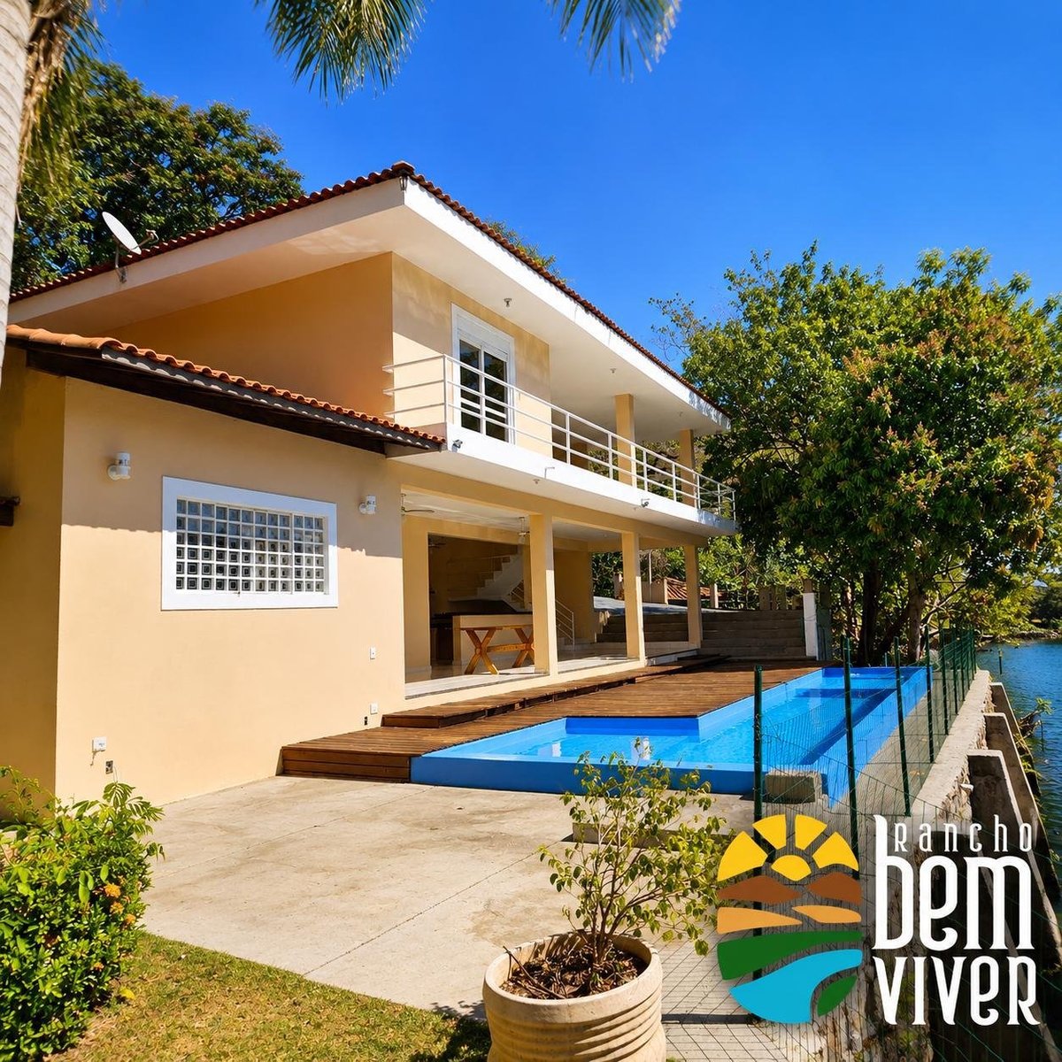 Fachada amarela do Rancho Bem Viver com piscina azul, deck de madeira e muito verde ao redor