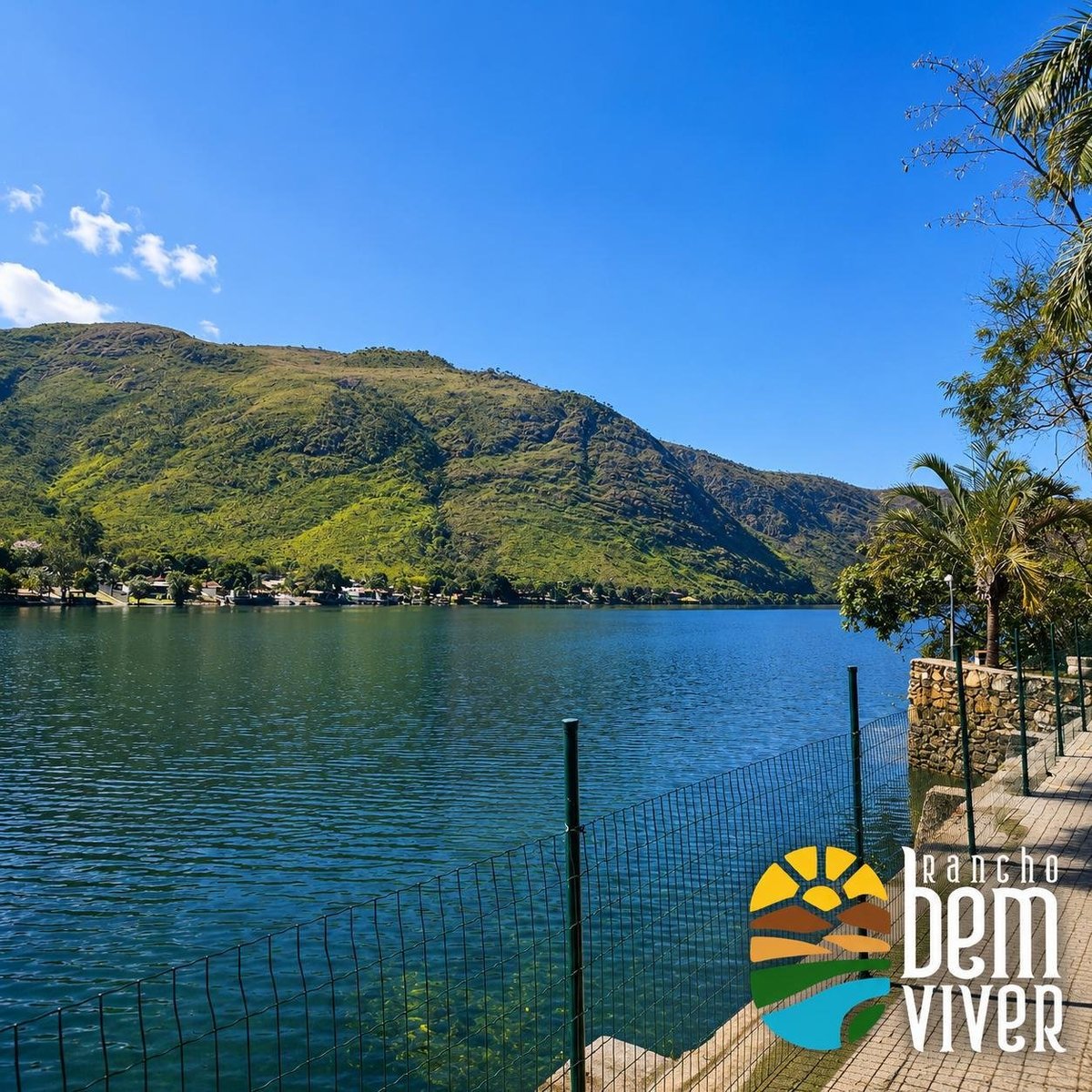 Vista do lago com montanhas verdes, deck de madeira e embarcadouro à beira d'água no Rancho Bem Viver
